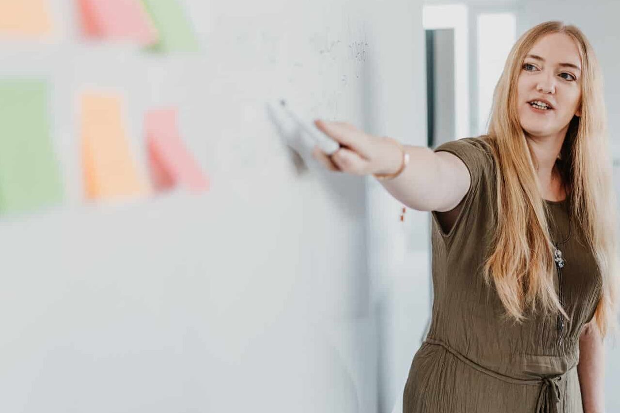 Mitarbeiterin erläutert Optimierungsmöglichkeiten im C-Teile-Management am Whiteboard