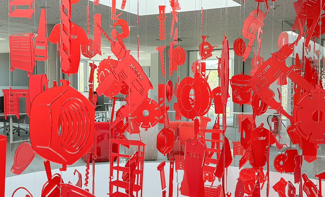 Rote Plexiglas-Silhouetten von Werkzeugen und C-Teilen – Symbol für vielfältige Materialien im C-Teile-Management