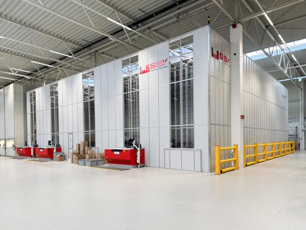 Blick auf das moderne AutoStore-System mit Kommissionierstationen in der Logistikhalle von SSV-Kroschke